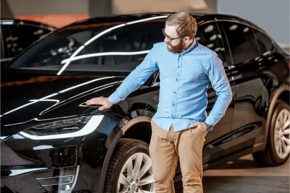 man strokes his new electric car ev with pride