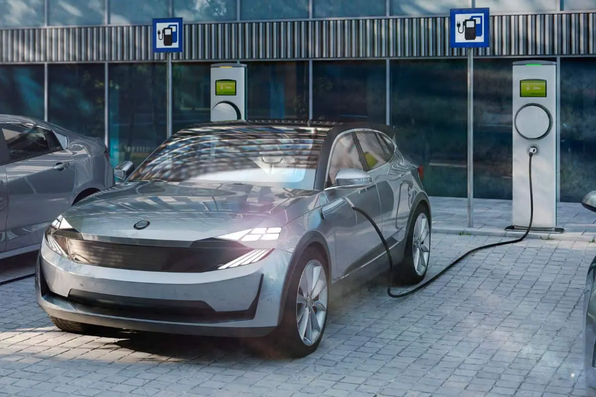 photo of a metallic grey electric vehicle car being charged at a roadside charging station