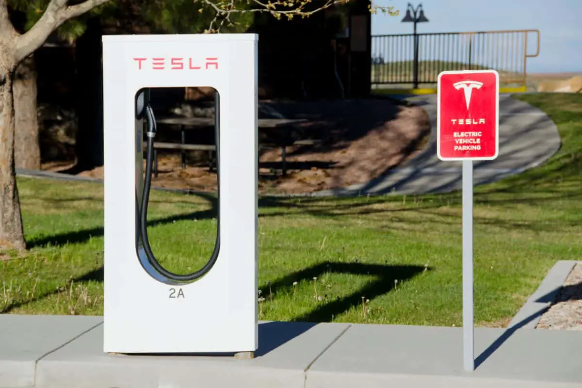 photo of a tesla street charger with red sign that says electric vehicle parking