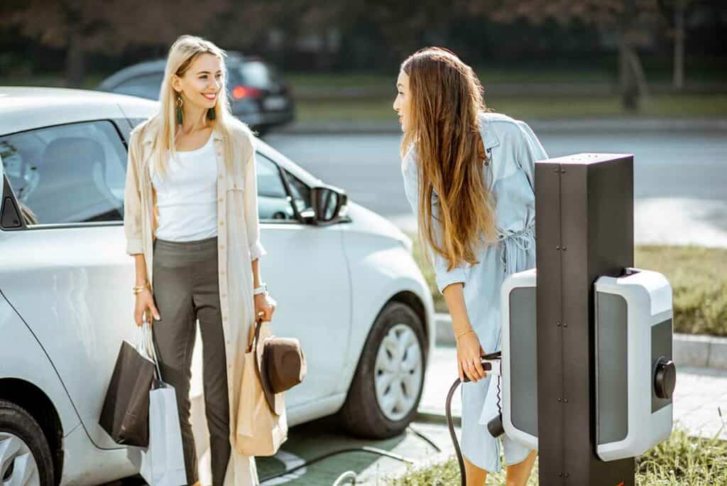 women-with-shopping-charging-electric-car-2022