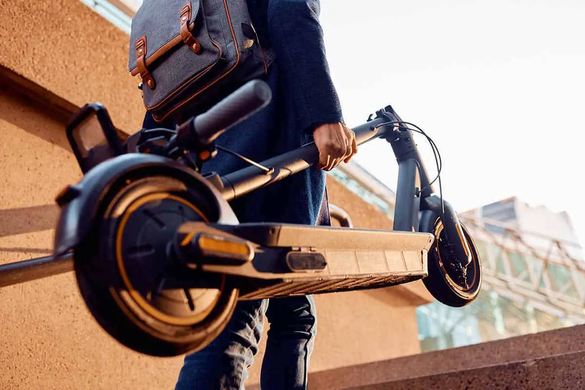 man walking up the stairs while carrying electric scooter