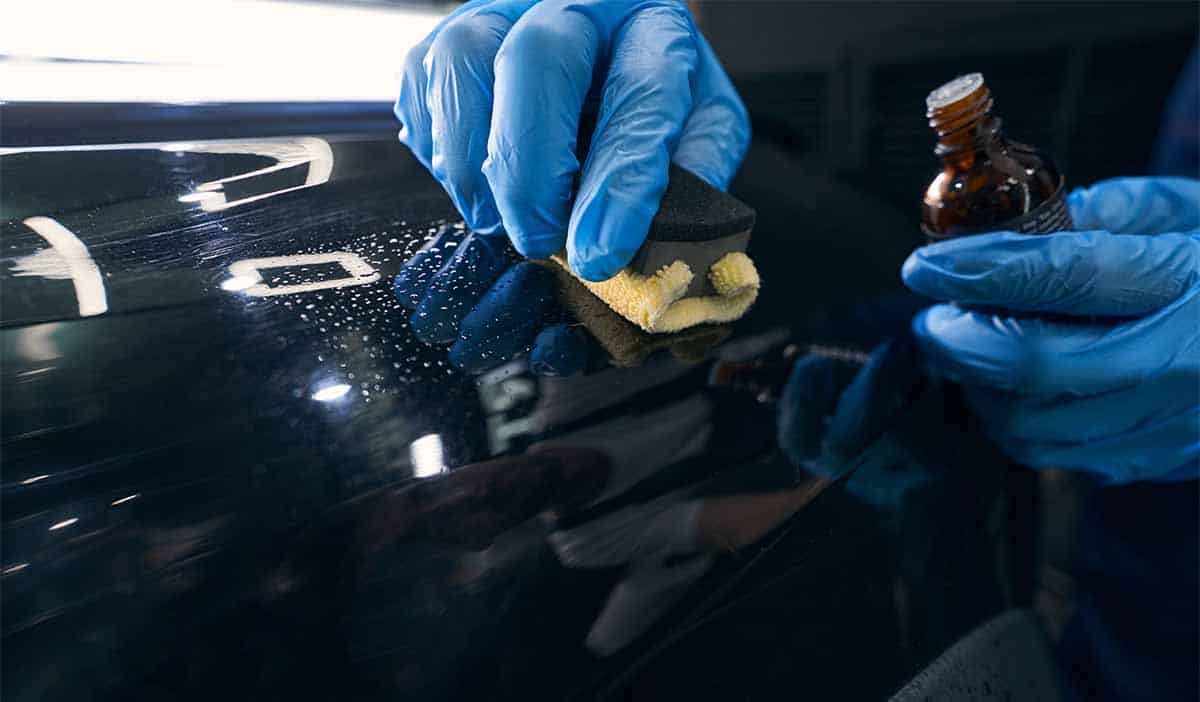 repairman applying ceramic coating to car surface crop