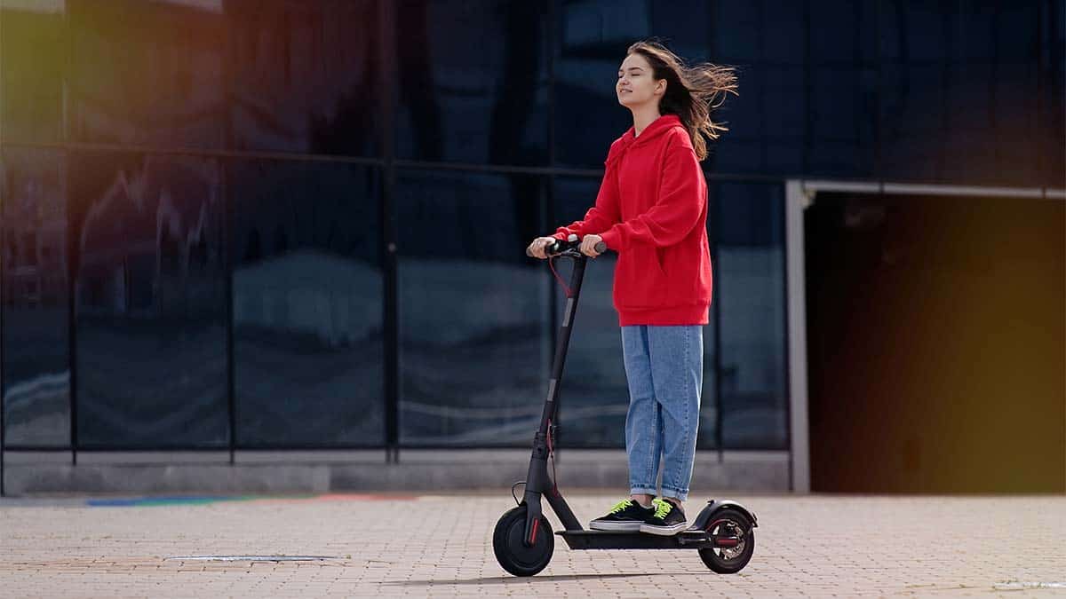 young girl riding on electric scooter hair blowing in the wind