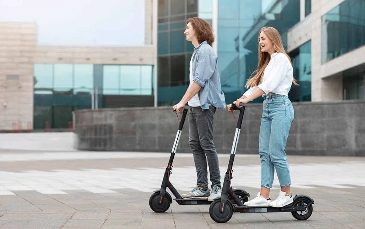 young-guy-and-lady-having-ride-on-electric-scooters