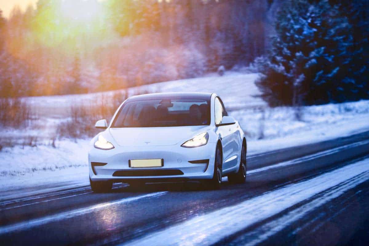 white tesla model 3 driving on snowy road
