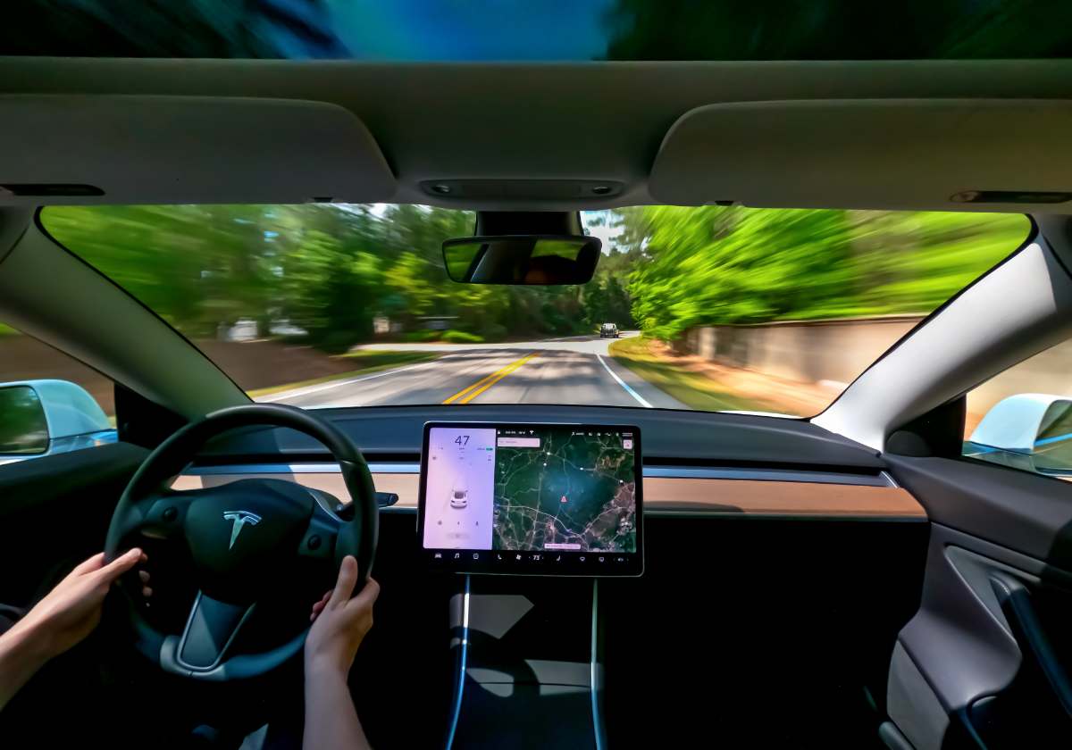 photo of interior of a new tesla model 3 on a road with motion blur, person driving with navigation on touchscreen